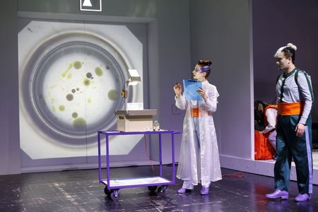 Ein Frau steht neben einem Overheadprojektor, im Hintergrund ein Bild von einem gro?en Reagenzglas